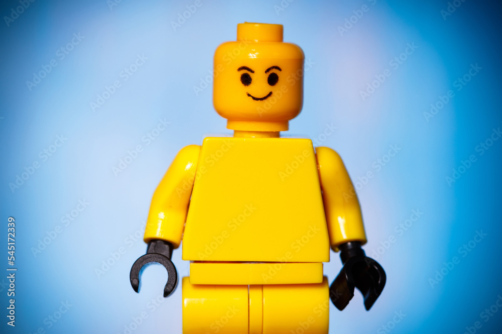 yellow lego figure with a smile on his face on a blue background with a  vignette Stock Photo | Adobe Stock