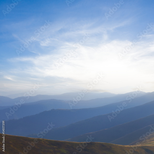 mountain chain silhouette in blue mist at the sunset, early morning mountain travel scene