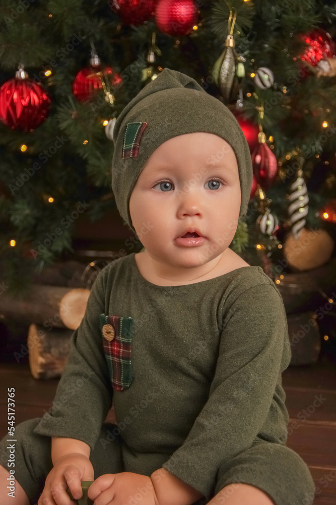 Cute little baby against blurred lights on dark background. Christmas celebration Cute little baby against blurred lights on dark background. Christmas celebration