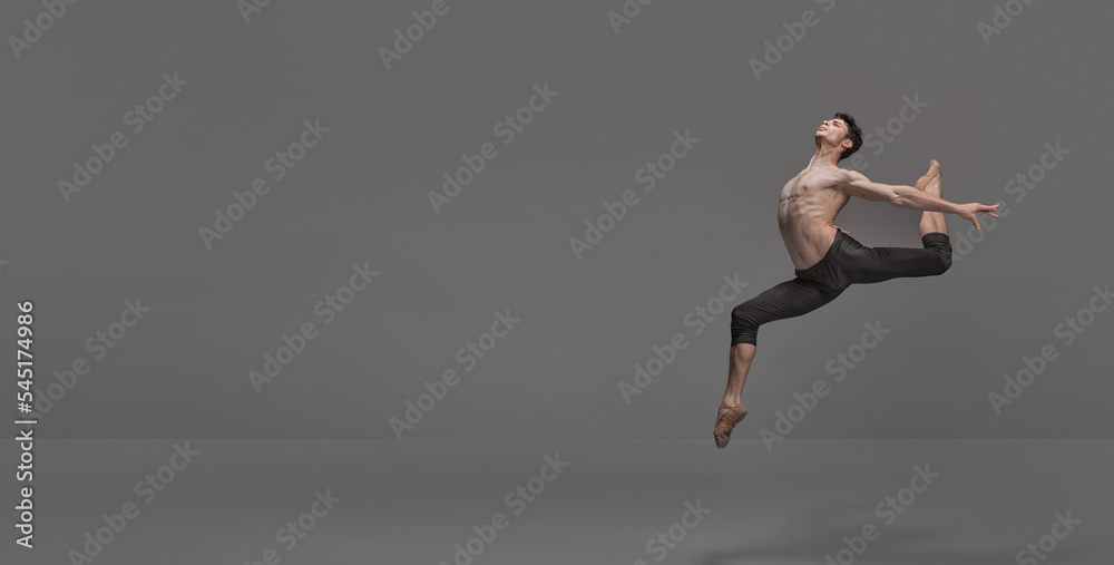 Portrait of young muscular man, ballet dancer performing on stage isolated over dark grey studio background. Flyer