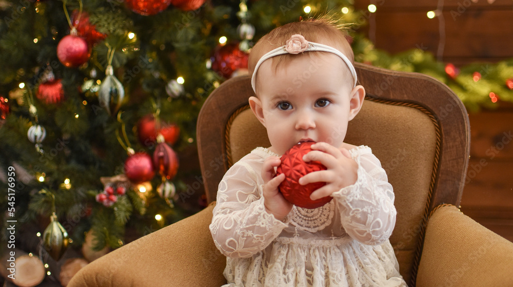 Cute little baby against blurred lights on dark background. Christmas celebration