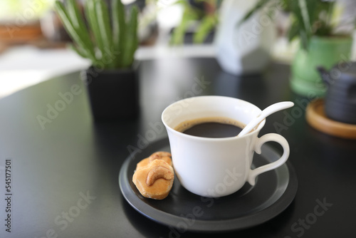 White coffee cup and cookie on black table