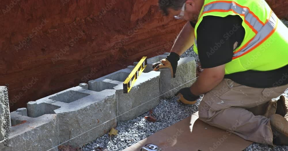 Contractor is induring the installation process of installing large block retaining wall constructed on construction site