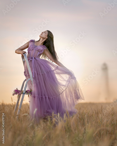 Girl in a lilac dress on the stairs in a wheat field