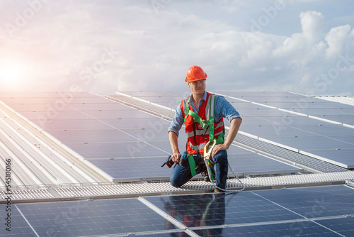 Wallpaper Mural Technician wearing safety harness belt using drill during installing the solar panels on roof structure of building factory. Torontodigital.ca