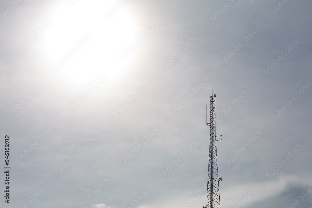 A radio or telephone tower in a backlit sky with the sun in the background. A radio or telephone tower in a backlit sky with the sun in the background.