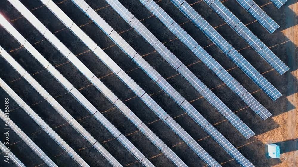 Rows of photovoltaic solar panels in a field at a solar power plant. Ecological production of electricity. Top view shot by drone.