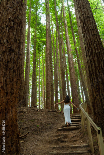 Young woman in white dress walking in the forest 