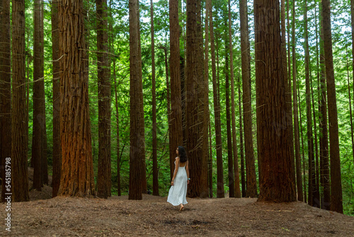 Young woman in white dress walking in the forest 