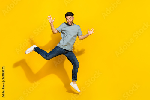 Full body portrait of satisfied glad person jumping raise hands empty space isolated on yellow color background