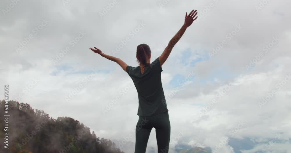 Woman raising hands in mountain, wide shot Woman raising hands in mountain, wide shot