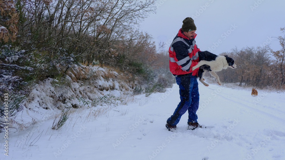 Hombre caucásico en la nieve jugando con perro Border Collie 