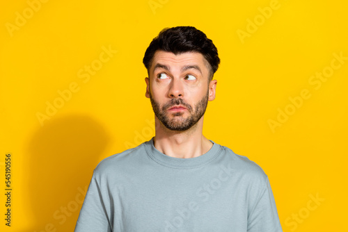 Photo of unsure uncertain man dressed stylish grey clothes interested look empty space isolated on yellow color background