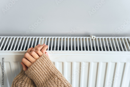 Kid freezing. Young girl freeze at home. Teenager girl in brown sweater, indoors on a chilly winter day, energy and gas crisis, cold room, heating problems