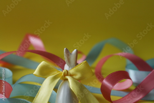 white rabbit, blue and pink ribbons, yellow background