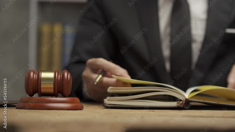 Young male lawyer working in the office Businessman or lawyer discussing laptop contract documents and judge's hammer with brass scales on table. 4k video. Young male lawyer working in the office Businessman or lawyer discussing laptop contract documents and judge's hammer with brass scales on table. 4k video.