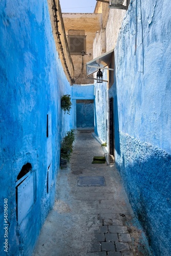 An empty narrow street with blue buildings in Chefchaouen © Hamza Makhchoune/Wirestock Creators