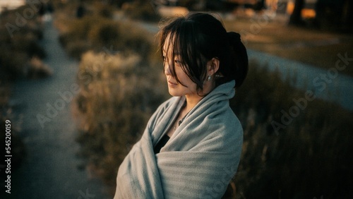 Foto Asian woman cuddled with a blanket on the coastline looking aside