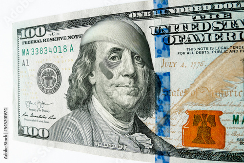 This photo illustration of Ben Franklin with a black eye and bandages on a newly printed 100 dollar bill might illustrate inflation, bad economy, recession, or misguided leadership. photo