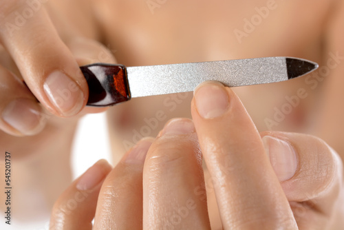Well-groomed woman at manicure filing fingernails with nail file