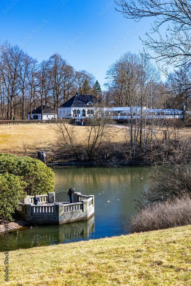 Fototapeta premium Vertical shot of a cottage at a lake shore on a sunny autumn day