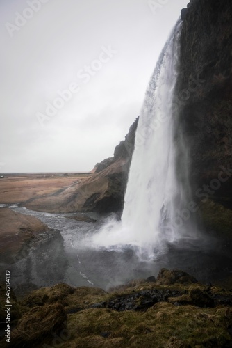 Vertical shot of the Skogafoss waterfall flowing down the cliff in Iceland on a gloomy day