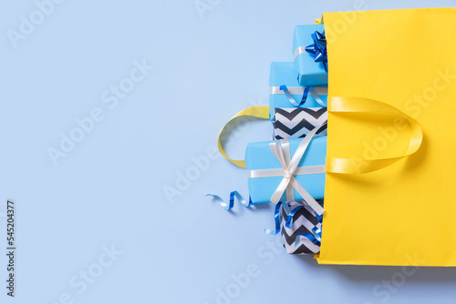 Christmas presents for the holidays concept. Holiday gift boxes with bows in a shopping bag on a color background