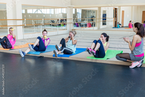 Women in the gym. Group aerobics with a trainer. Cute beauties in bright sportswear. Be active and take care of yourself.
