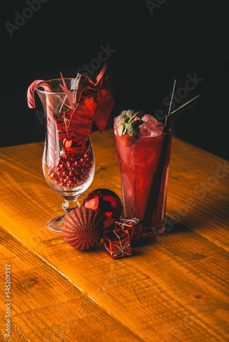 Vertical shot of strawberry cocktail, a glass filled with Christmas marbles, with a candy crane