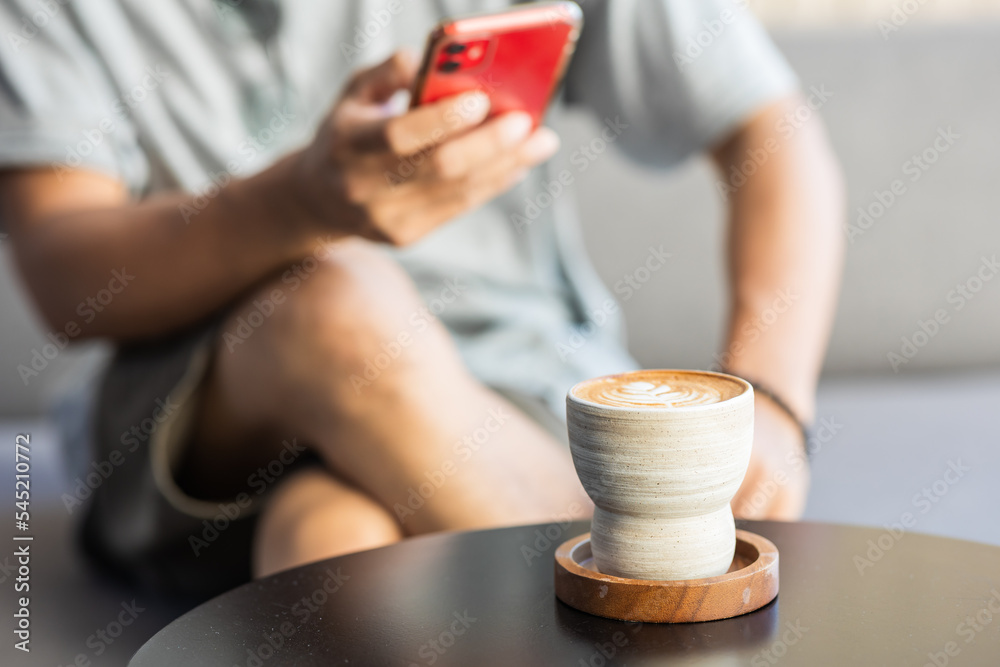 Close-up of a man using a smartphone in a coffee shop.