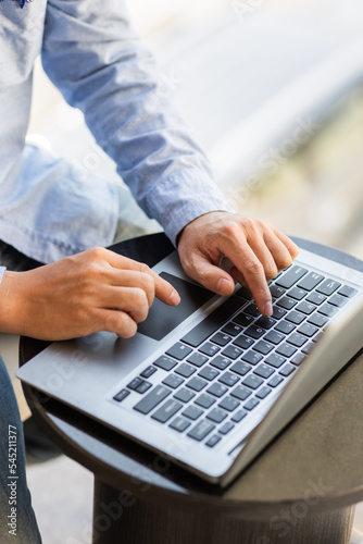 Side view of male businessman hands typing on laptop keyboard.