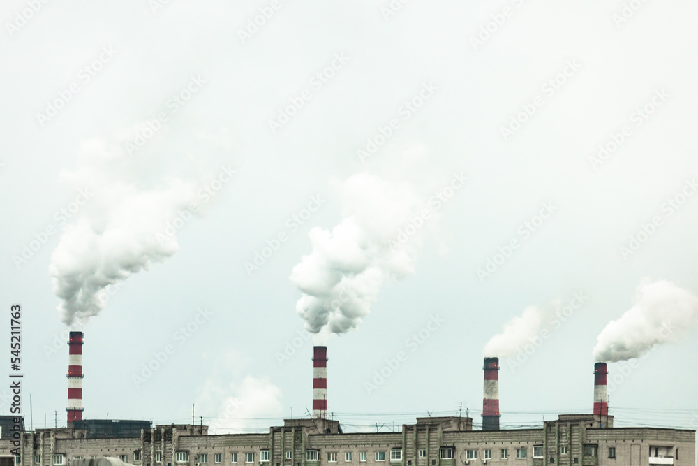 industrial chimneys with heavy smoke causing air pollution on the gray smoky sky background
