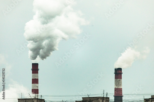 industrial chimneys with heavy smoke causing air pollution on the gray smoky sky background
