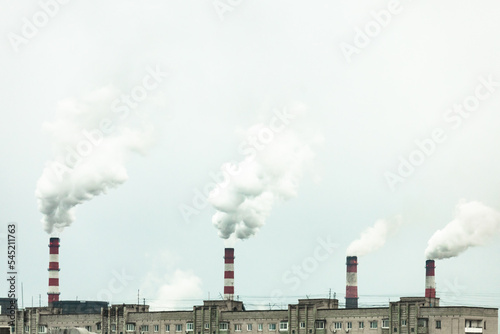 industrial chimneys with heavy smoke causing air pollution on the gray smoky sky background 