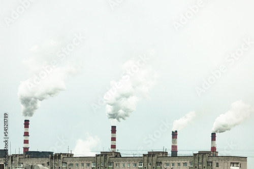 industrial chimneys with heavy smoke causing air pollution on the gray smoky sky background

