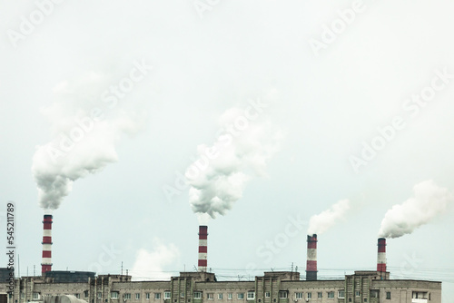 industrial chimneys with heavy smoke causing air pollution on the gray smoky sky background 