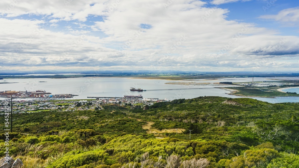 Fototapeta premium Panoramic view of a ship sailing in the sea near a green forest in Invercargill, New Zealand