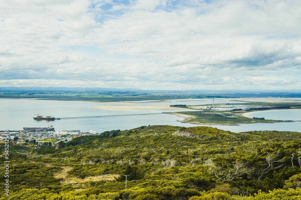 Obraz premium Panoramic view of a ship sailing in the sea near a green forest in Invercargill, New Zealand