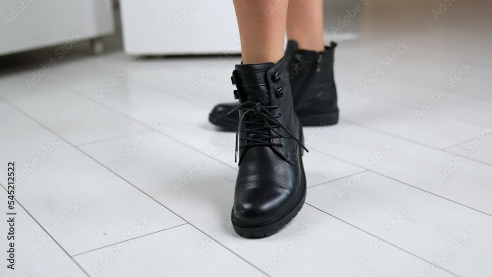 Bare-legged model demonstrating low black leather boots with laces. Woman rises foot to shoe the tractor sole of footwear. Close up. Bare-legged model demonstrating low black leather boots with laces. Woman rises foot to shoe the tractor sole of footwear. Close up.