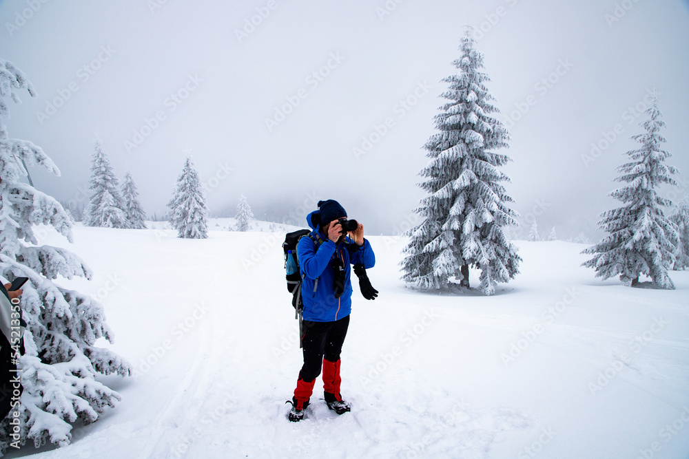 man trekking in magical frozen winter landscape with snow covered fir trees