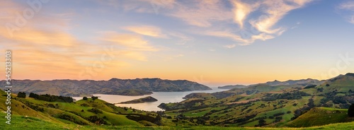 Panoramic shot of a green meadow in front of a lake, Akaroa, Banks Peninsula, New Zealand