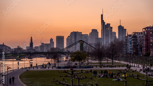 Beautiful shot of a crowded park against modern buildings in Frankfurt, Germany at sunset