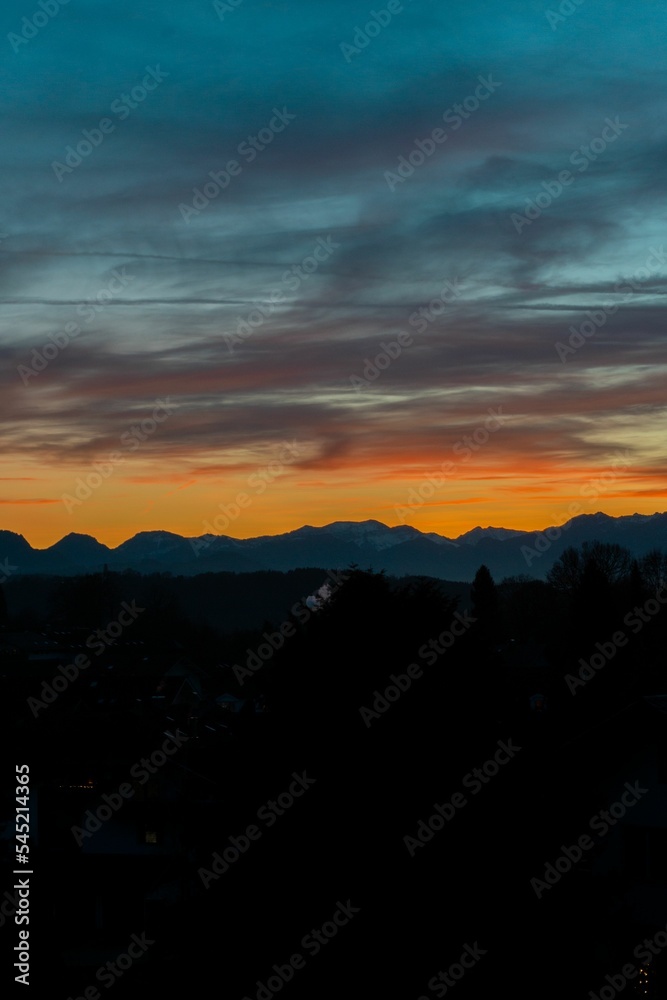 Fototapeta premium Vertical silhouette shot of alps and hills with a beautiful sunset in the background