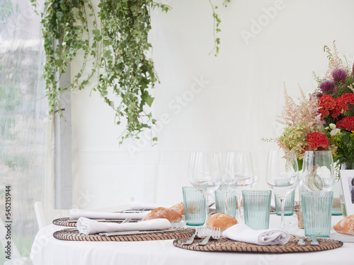 wedding decoration Nature Style with green leaves plants. Table setting with flowers. White tablecloth and white background with copy space