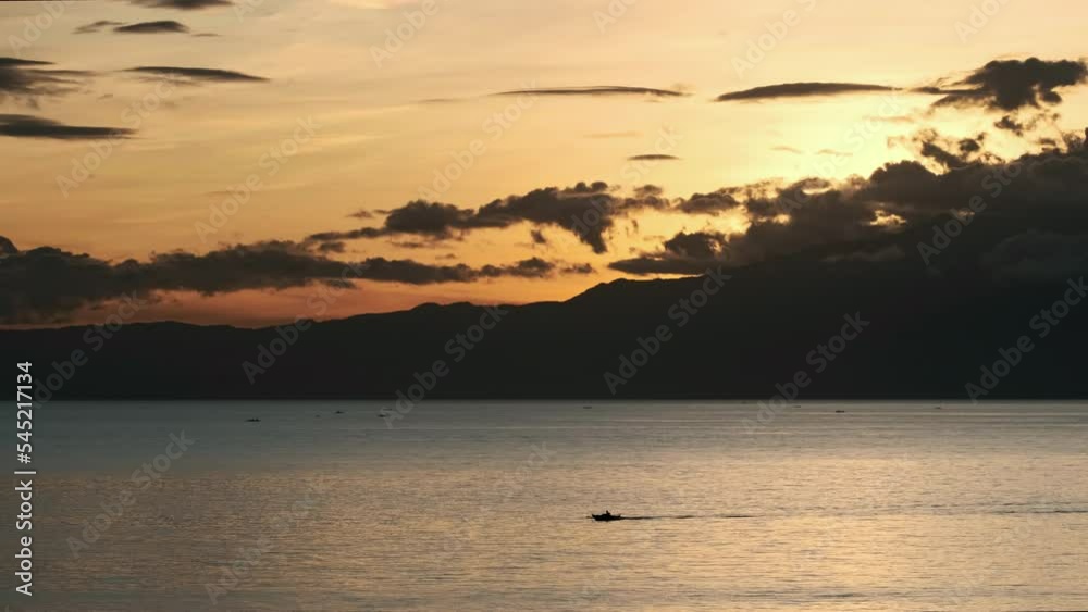 View of the small fishing boat crossing the sea at sunset. Siquijor Island, Philippines. View of the small fishing boat crossing the sea at sunset. Siquijor Island, Philippines.