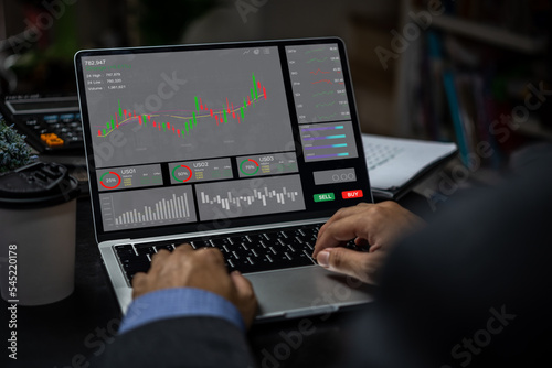 Businessman trader looking on laptop with graphs analysis candle line report stock market diagram profit.