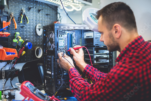 IT engineer technician repairing computer in electronics service shop photo