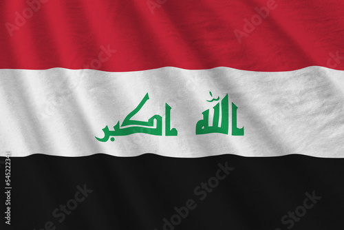 Iraq flag with big folds waving close up under the studio light indoors. The official symbols and colors in banner