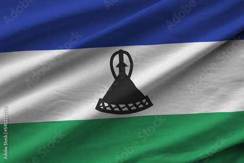 Lesotho flag with big folds waving close up under the studio light indoors. The official symbols and colors in banner photo