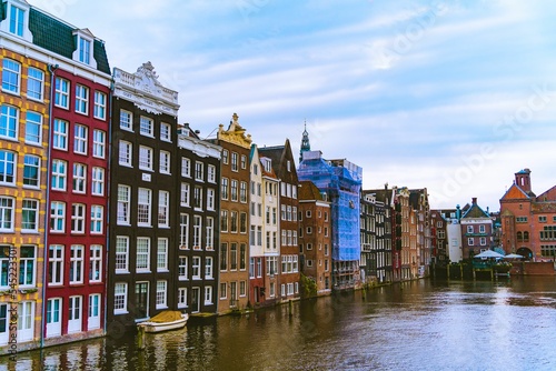 Damrak avenue buildings with a boat in a canal, Amsterdam, the Netherlands © Evan Yang1/Wirestock Creators